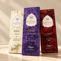 Three Satvic Devotion incense sticks in decorative packaging, featuring Jasmine in cream, Lavender in purple, and Rose in deep red, standing upright on a light surface.