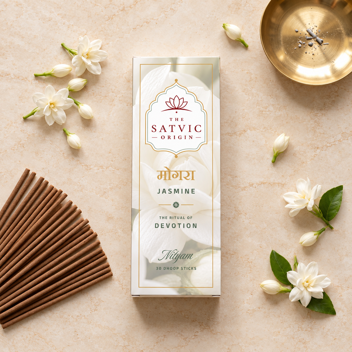 A boxed incense stick set from The Satvic Origin, specifically Jasmine, arranged in a styled flat-lay on a light beige textured surface with white jasmine flowers, incense sticks, and a gold dish.