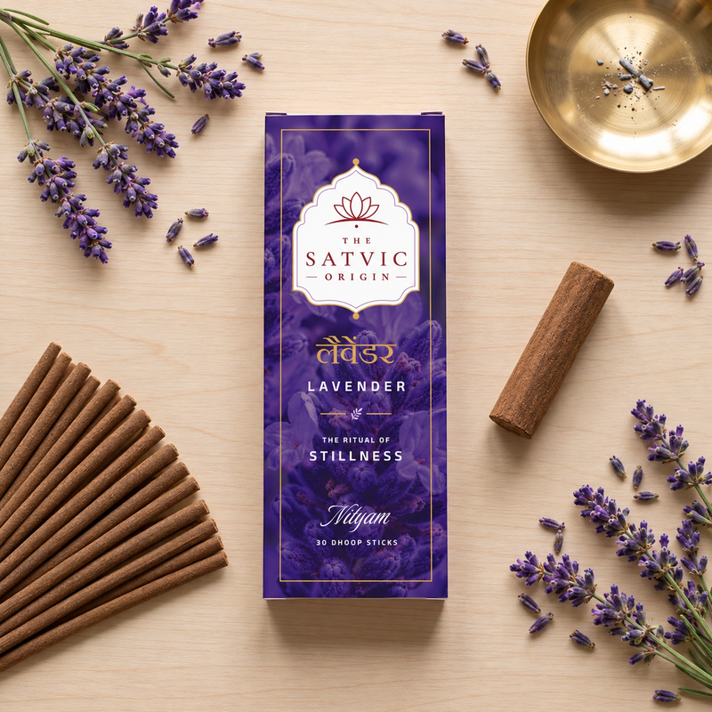 A flat-lay of The Satvic Origin Lavender Naima incense box on a light wood surface, surrounded by lavender sprigs, wooden sticks, and a brass incense burner.